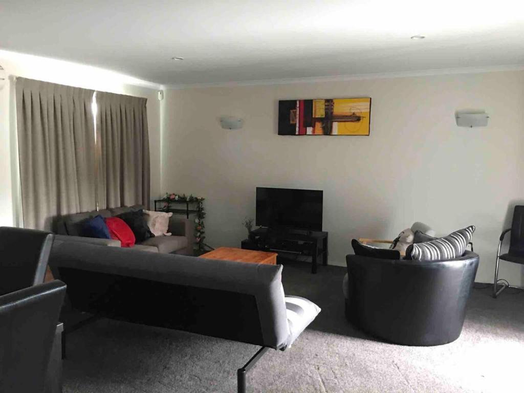 a living room with couches and chairs and a television at Comfortable Home Close to Airport in Christchurch