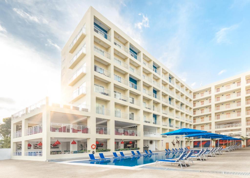 un gran hotel blanco con sillas azules y una piscina en Decameron La Marina en Rincon de Guayabitos