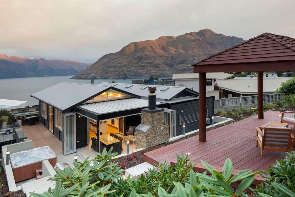 a house with a deck with a view of the water at Mountain Vista - beautifully renovated home with spa pool in Queenstown