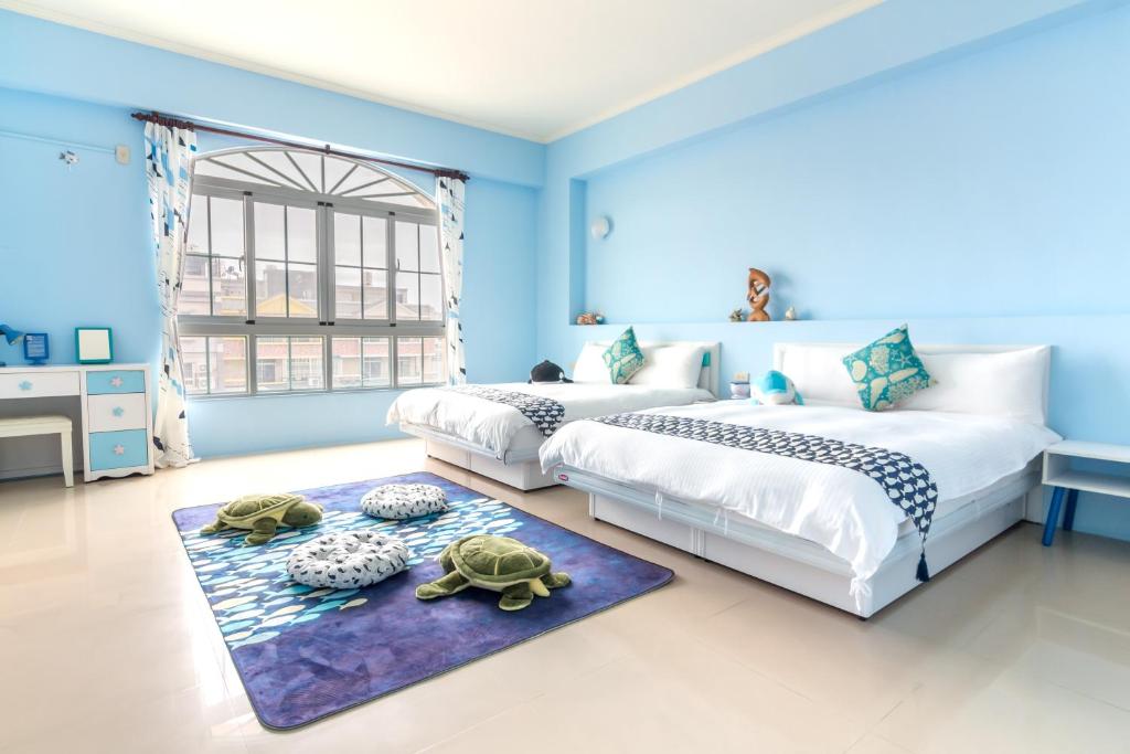 duas camas num quarto azul com duas tartarugas num tapete em Ciao Life B&B em Taitung City