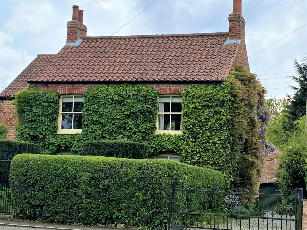 a house covered in ivy with a fence in front at Country chic in unique English village in Nun Monkton