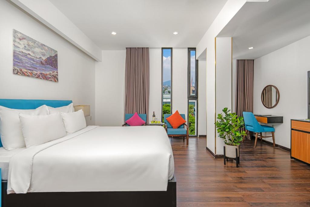 a bedroom with a large white bed and blue chairs at Platinum Danang Hotel in Da Nang