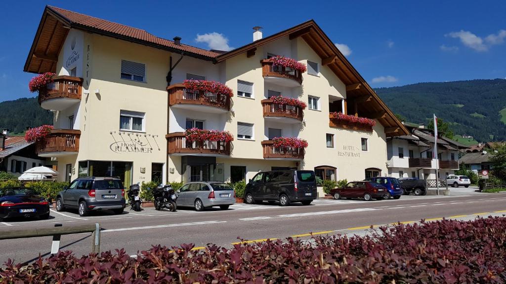 a large building with cars parked on the side of a road at Hotel Klammer in Vipiteno