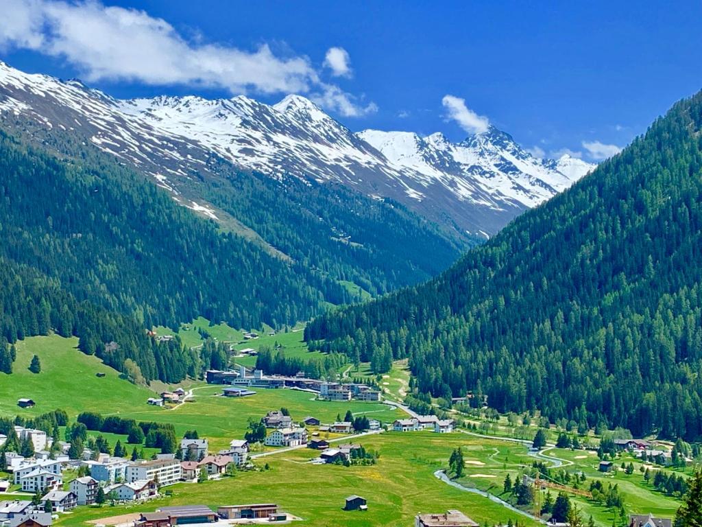 a small town in a valley with snow covered mountains at Ferienwohnung Sunneschii in Davos