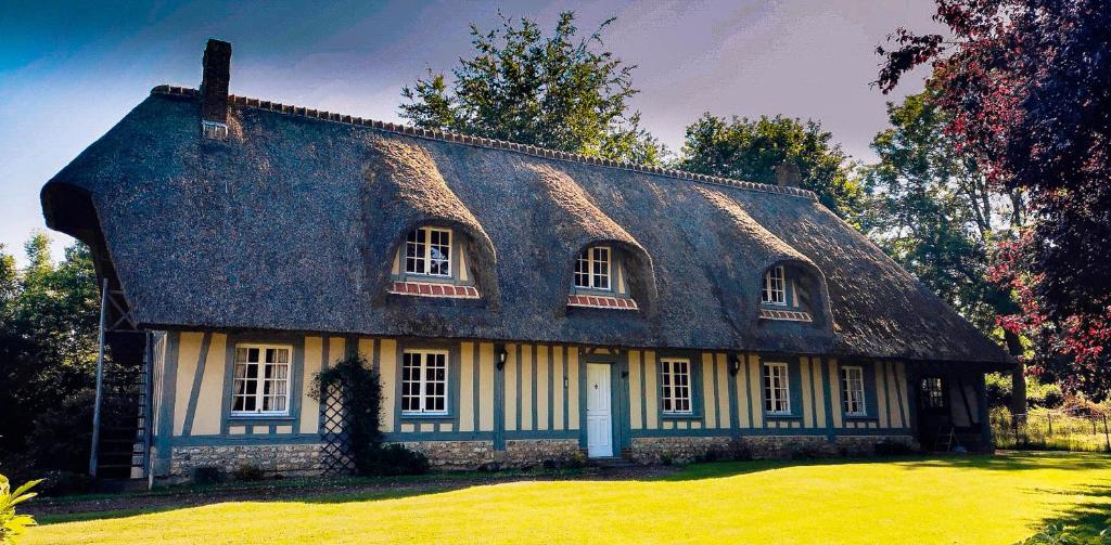 ein altes Haus mit einem Strohdach auf einem Rasen in der Unterkunft chaumière de l'épine in La Crique