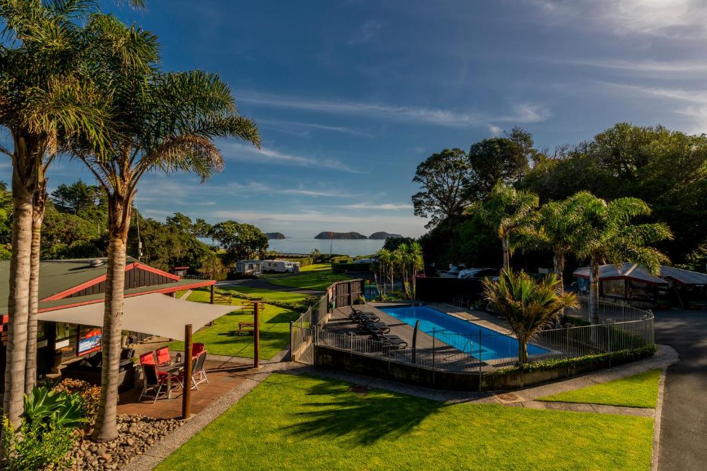 uma imagem de um resort com uma piscina e palmeiras em Anglers Lodge em Coromandel Town