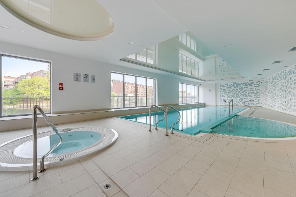 a swimming pool with a hot tub in a building at Apartinfo Apartments Waterlane Island SPA in Gdańsk