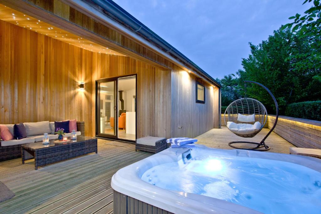 eine Whirlpool-Badewanne auf einer Terrasse neben einem Haus in der Unterkunft Orchard Lodge, Strawberryfield Park in Cheddar