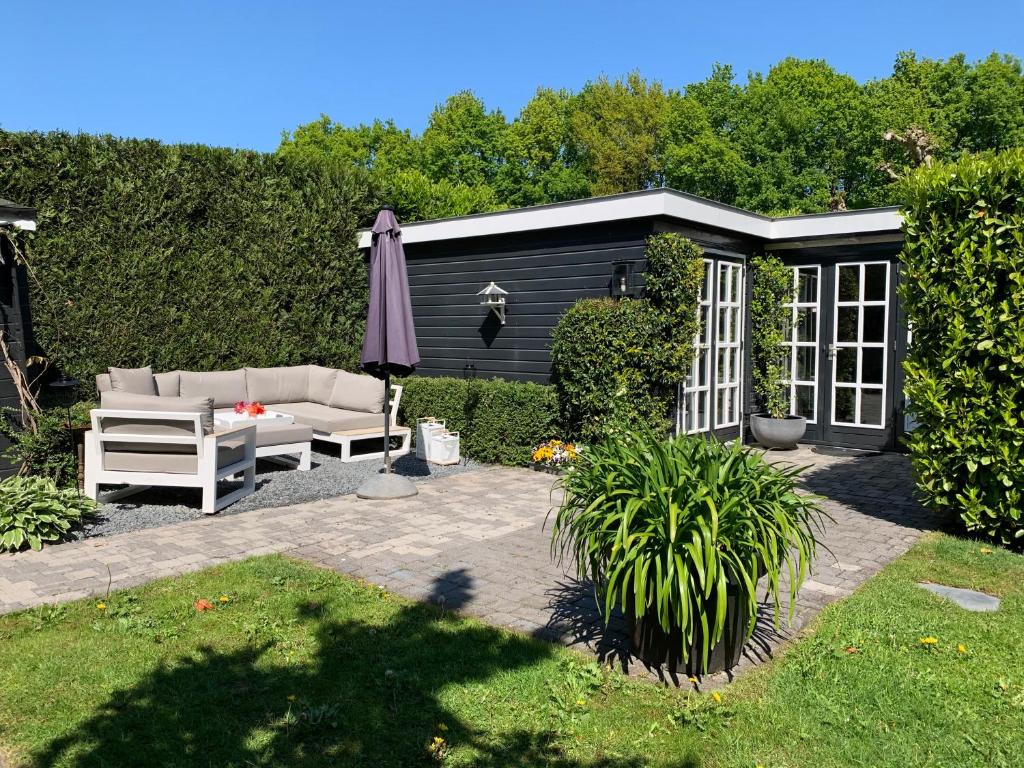 a patio with a couch and an umbrella and a garden at Place To Be in Naarden