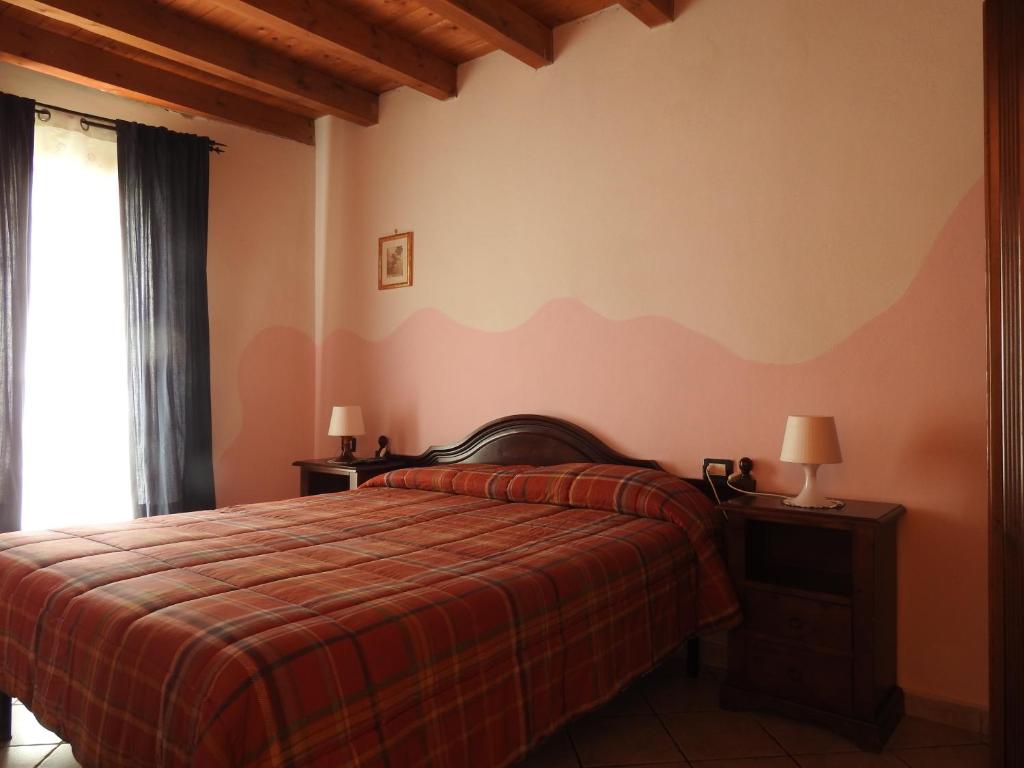 um quarto com uma cama com um edredão vermelho em Affittacamere "Nel Paese di Alice" em Borghetto di Vara