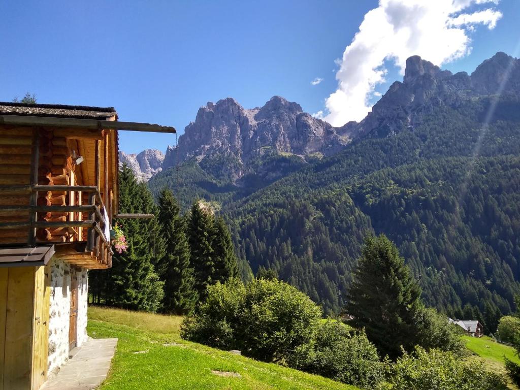 une maison sur une colline avec des montagnes en arrière-plan dans l'établissement The "small" Alpine Chalet & Dolomites Retreat, à San Martino di Castrozza