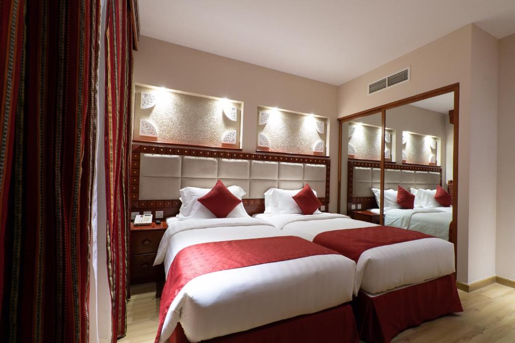 a hotel room with two beds and a mirror at Al Liwan Suites Rawdat Al Khail in Doha
