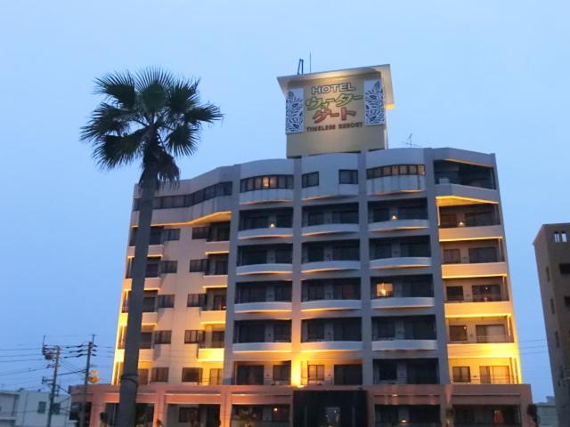 ein hohes Gebäude mit einer Palme davor in der Unterkunft ウォーターゲート鹿児島 in Kagoshima