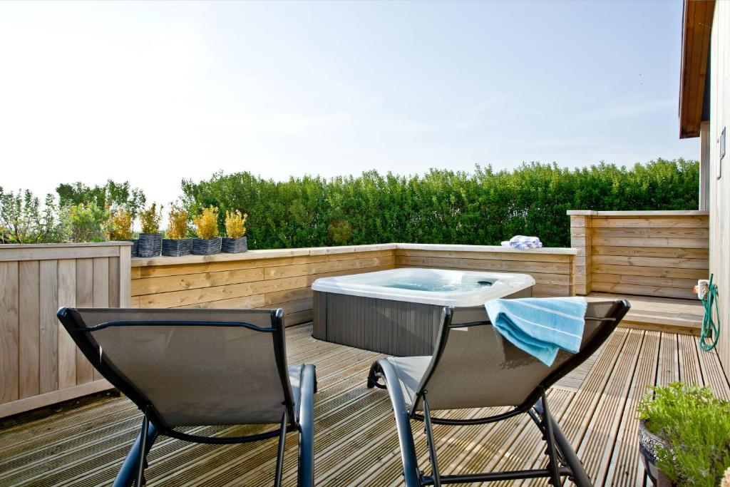 a deck with two chairs and a table and a hot tub at Pomegranate, Strawberryfield Park in Cheddar