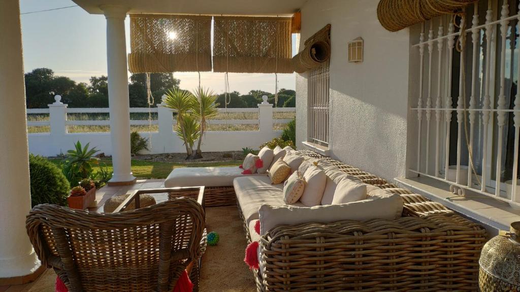 - un salon avec des canapés et des chaises en osier sur une terrasse couverte dans l'établissement Alma Caños de Meca, à Los Caños de Meca