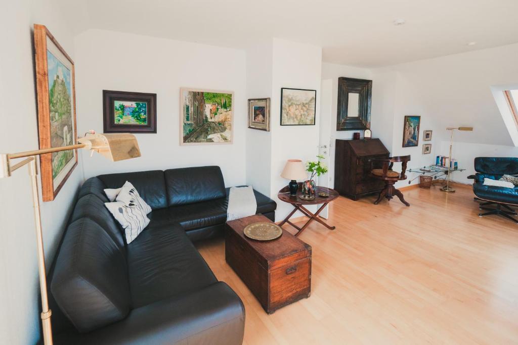 a living room with a black leather couch and a piano at Apartment Flair in Lübeck