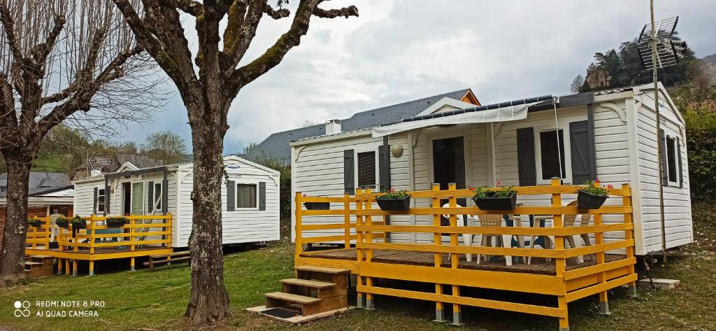 une rangée de mobile homes garés à côté d'un arbre dans l'établissement Mobil-home au pied des Pyrénées, à Castillon-en-Couserans