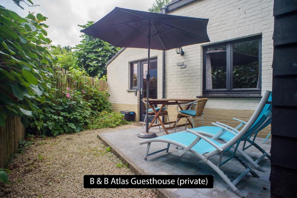 a patio with two chairs and a table with an umbrella at Atlas Private Guesthouse in Bruges