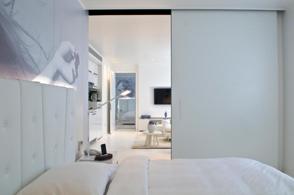 a bedroom with a white bed and a living room at B-aparthotel Regent in Brussels