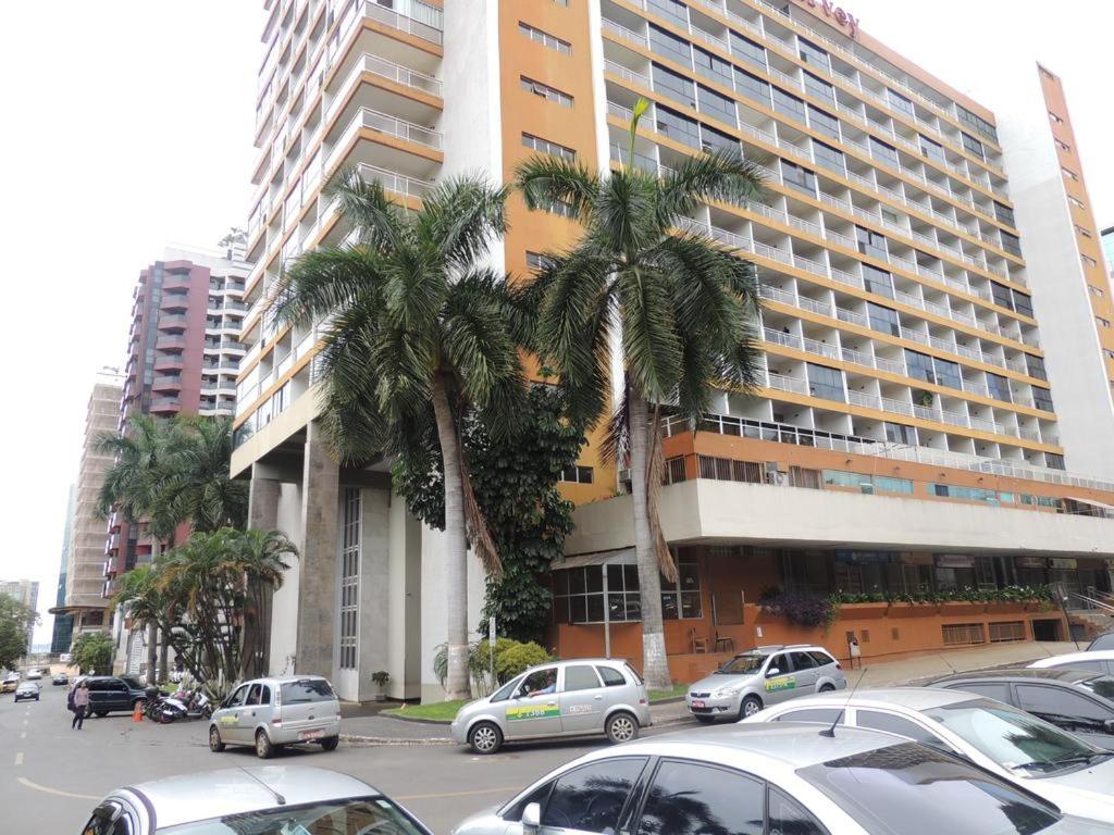 un aparcamiento con coches estacionados frente a un gran edificio en Ikeda Hoteis, en Brasilia