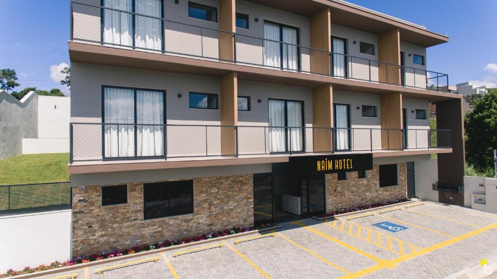 an exterior view of a building with a parking lot at NAIM Hotel in Capitólio