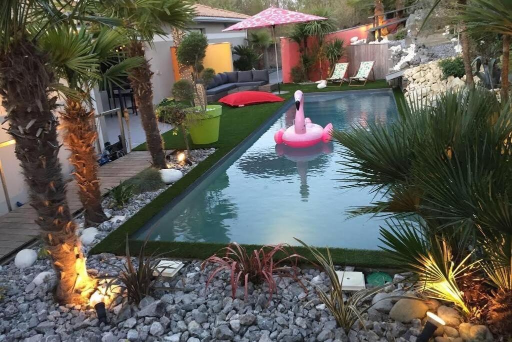 una piscina en el patio trasero con un flamenco rosa en el agua en Maison entre bordeaux et le bassin d'arcachon avec piscine et jaccuzi 2 a 6 pers en Saint-Jean-dʼIllac