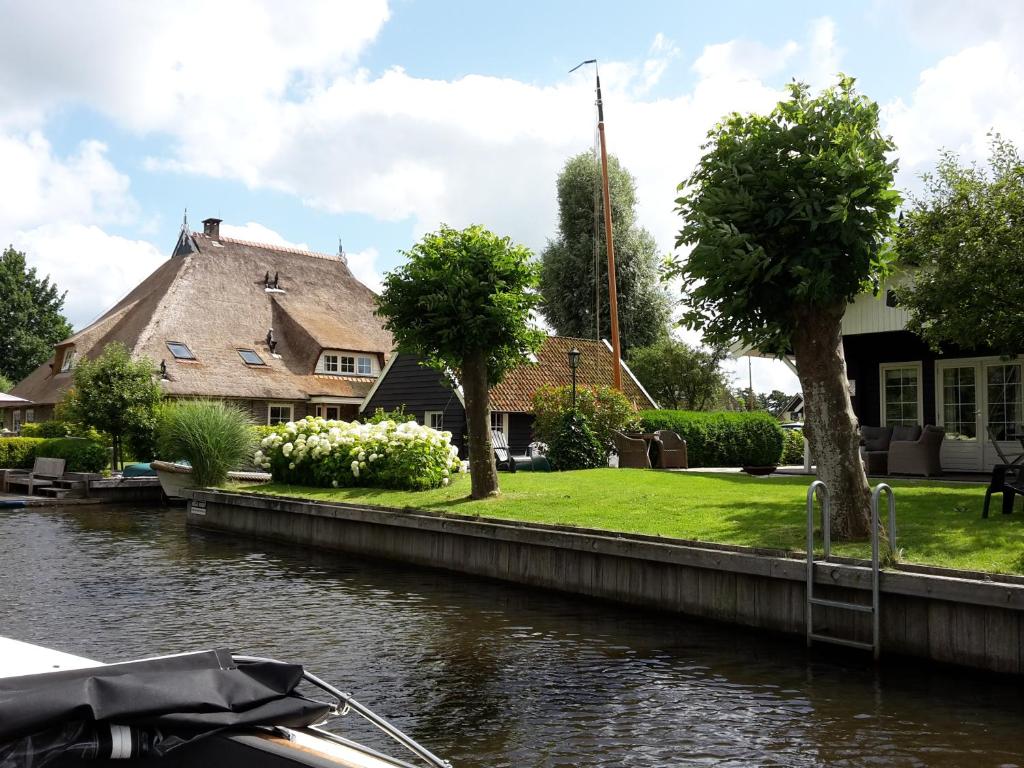 una casa junto a un río con un barco en d'Oude Herbergh, vakantiehuizen aan het water en Terherne