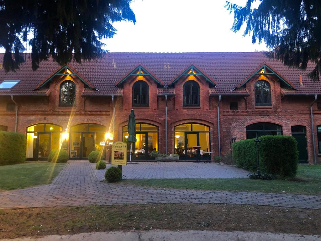 un gran edificio de ladrillo con un patio delante de él en Gästehaus Schlossgarten, en Etelsen