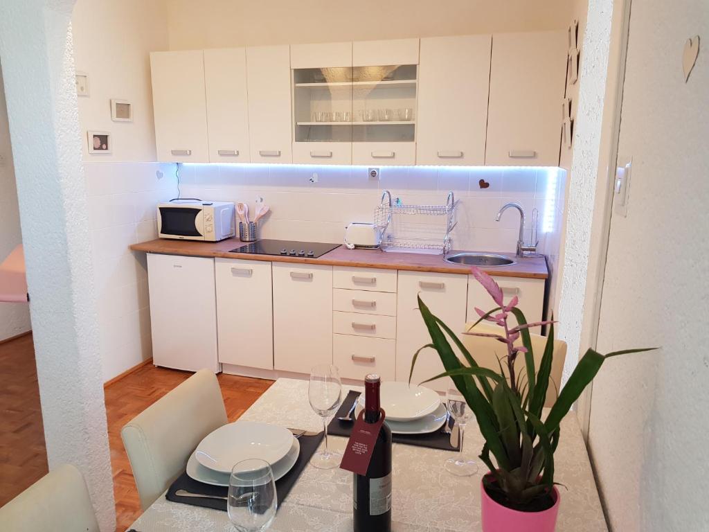 una cocina con armarios blancos y una mesa con una planta en Apartment Anna 2021 en Poreč