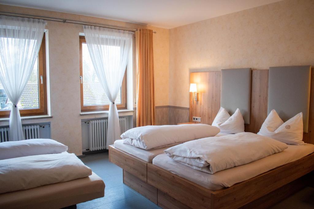 a bedroom with two beds and two windows at Hotel Garni Illertal in Altenstadt