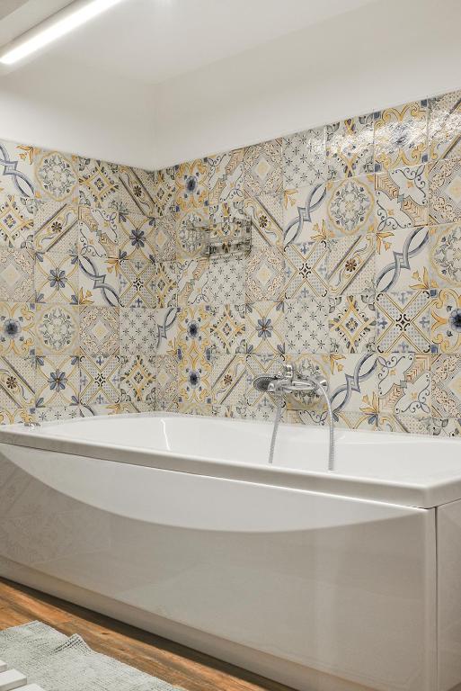 W łazience z podłogą wyłożoną kafelkami znajduje się wanna. w obiekcie Filomena Suite Luxury Apartment w Katanii