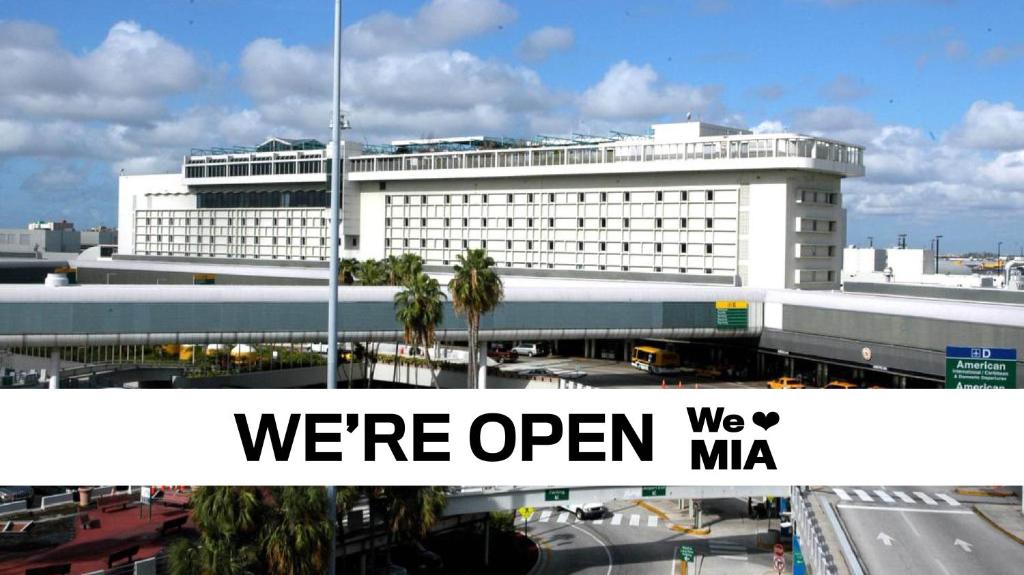 a white building with a sign that says were open at Miami International Airport Hotel in Miami