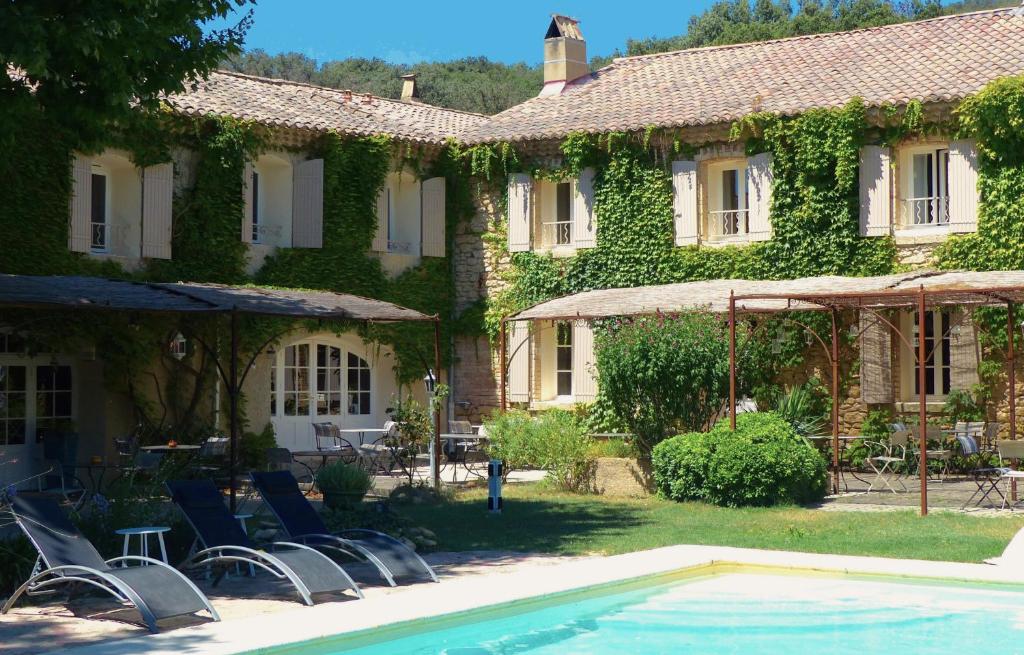 a house with a swimming pool in front of a building at Logis Hôtel Restaurant La Sommellerie in Châteauneuf-du-Pape