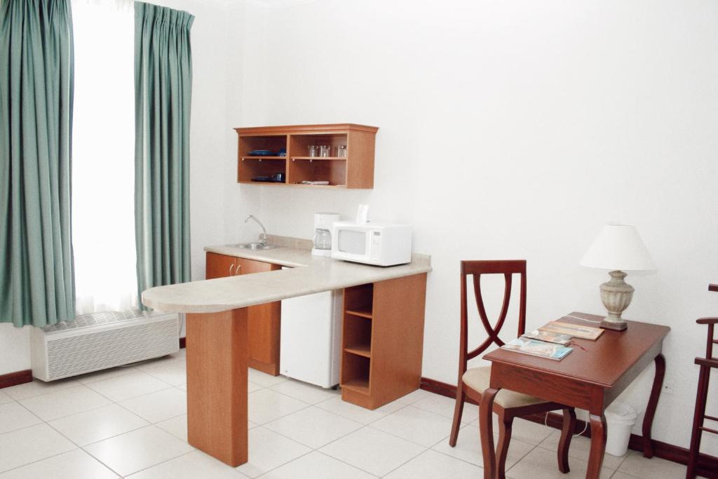 a kitchen with a desk and a table with a microwave at Hotel Mirador Plaza in San Salvador