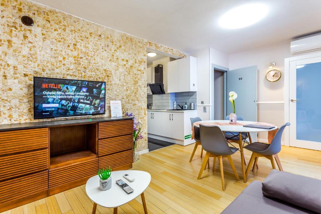 - un salon avec une télévision, une table et des chaises dans l'établissement JessApart– Babka Tower Apartment, à Varsovie