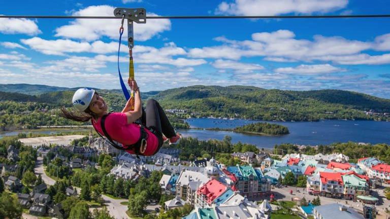a woman is hanging from a zip line at Chalet Le Pélican in Lac-Superieur