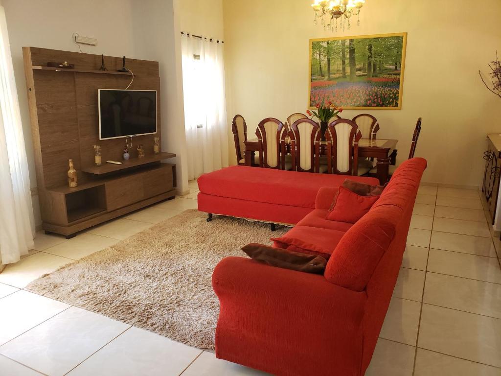uma sala de estar com um sofá vermelho e uma televisão em Angel Family Houses em Foz do Iguaçu
