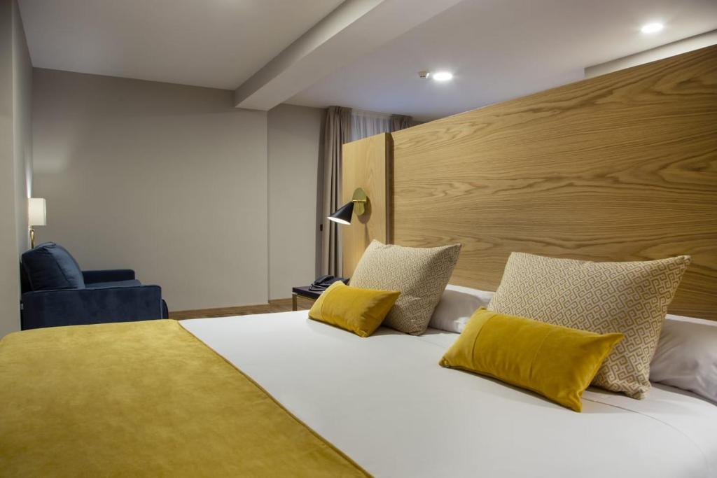 a bedroom with a large bed with yellow pillows at Hotel Zentral Mayoral in Toledo