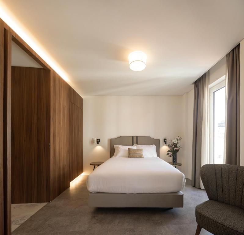 a bedroom with a white bed and a chair at Lisbon Serviced Apartments - Avenida in Lisbon