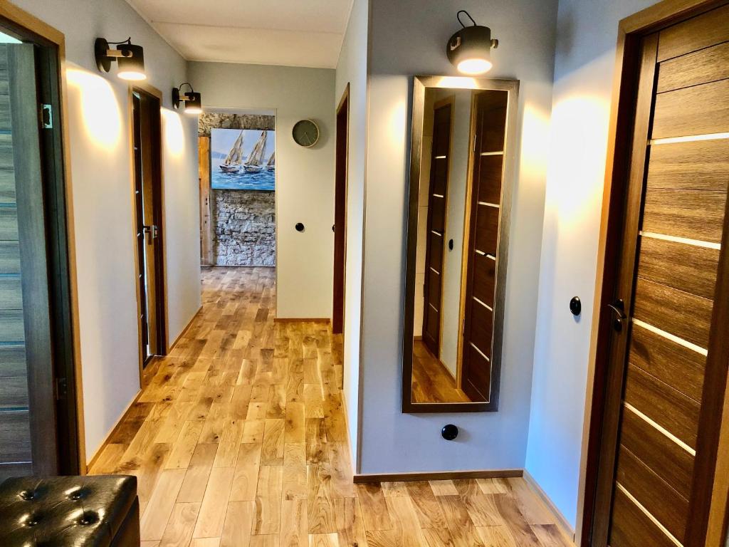 a hallway with wood floors and a mirror at Kohtu Apartment Epoch in Kuressaare