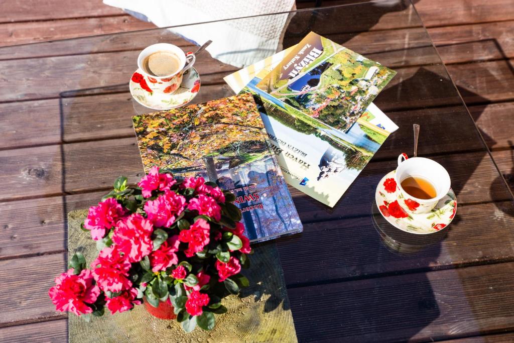 stół z kwiatami, książka i filiżanka kawy w obiekcie Chata Pod Świnią Górą w mieście Bliżyn