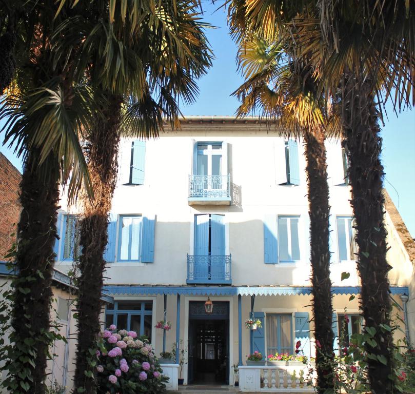 une maison blanche avec des palmiers devant elle dans l'établissement HOTEL MARCEILLAC, à Castelsarrasin