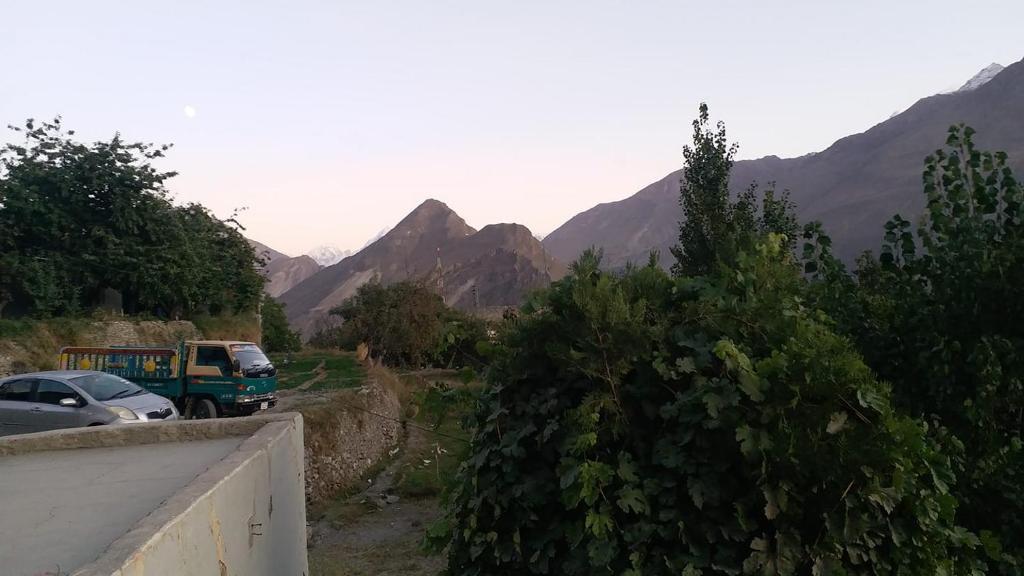 un coche aparcado en una carretera con montañas en el fondo en Ibadat Shah Lodges, en Baltit