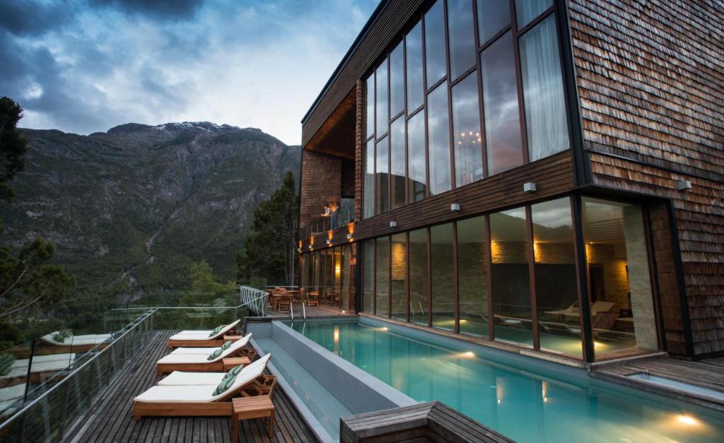 a house with a swimming pool and mountains at Uman Lodge Patagonia Chile in Futaleufú