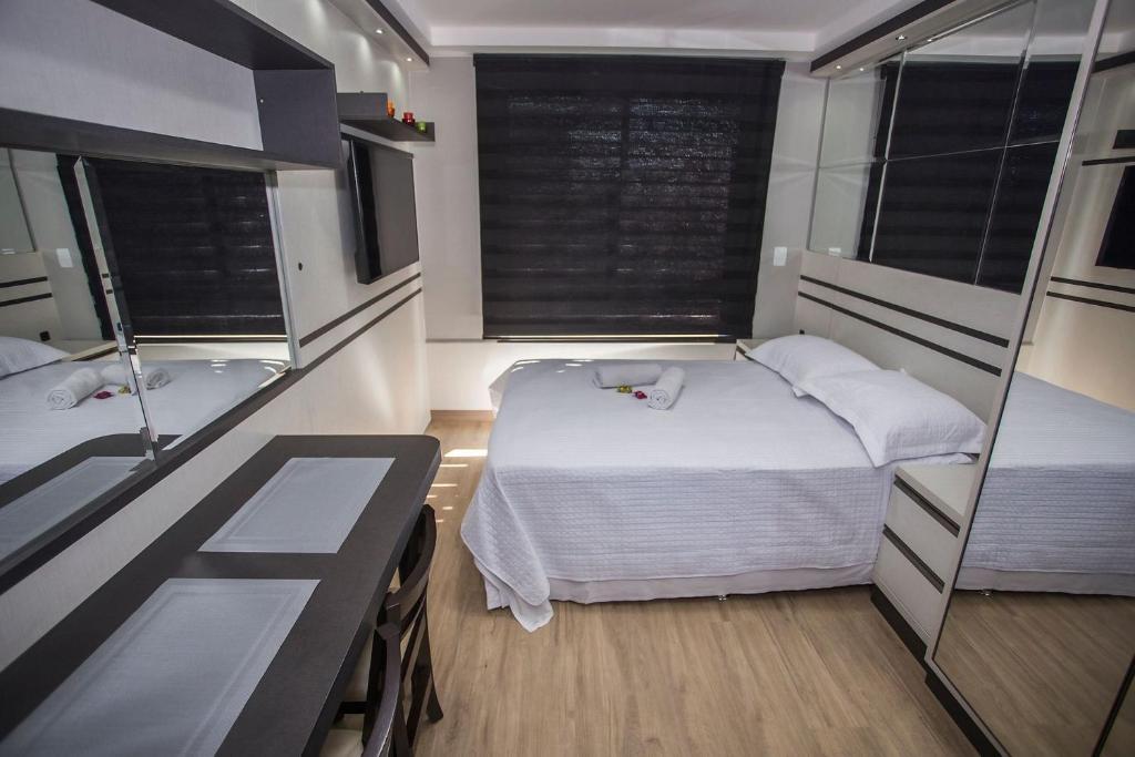 a bedroom with two beds and a tub and a sink at Studio Moderno no Centro de Curitiba - ALL1206 in Curitiba