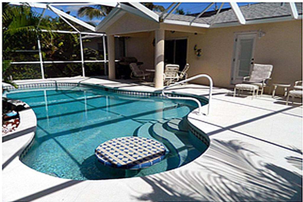 a swimming pool with two chairs in a house at Mango Marco in Marco Island