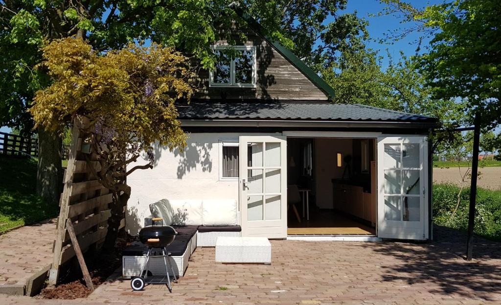 einen kleinen weißen Schuppen mit einer Tür und einer Terrasse in der Unterkunft Gastenverblijf Goudswaard in Goudswaard