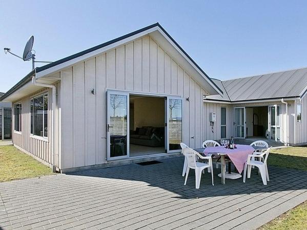 una casa con tavolo e sedie su una terrazza di Lochaber Lodge - Acacia Bay Holiday Home a Taupo