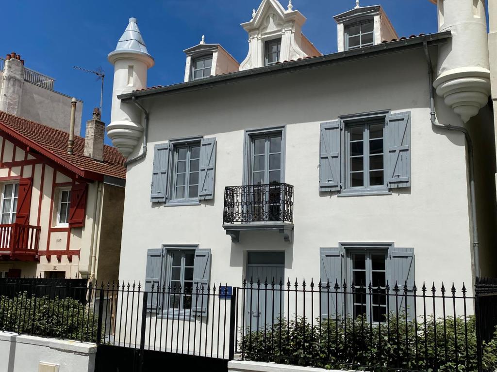 une maison blanche avec une clôture devant elle dans l'établissement Les Tourelles, à Biarritz