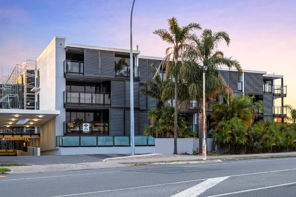 an empty street in front of a building with palm trees at Rooftop Retreat - Mount Maunganui Holiday Home in Mount Maunganui